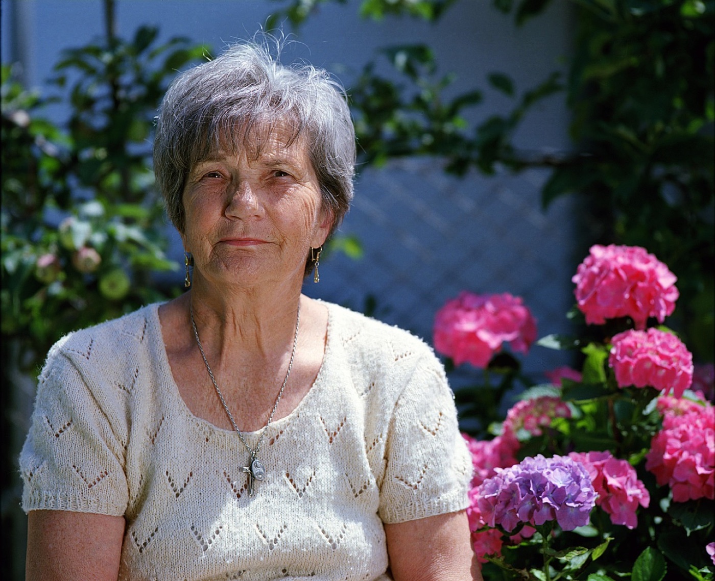 Oudere cliënt geniet buiten in een kleurrijke tuin